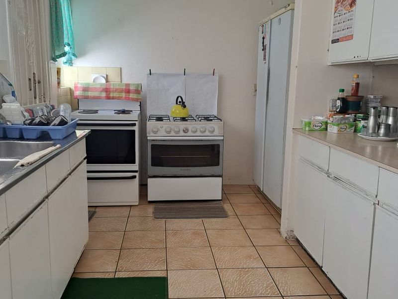 A functional kitchen featuring tiled flooring, built-in cabinetry, laminate countertops, and a gas stove, offering potential for modernization and cosmetic updates.