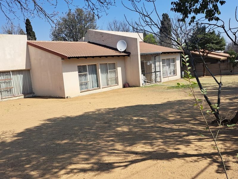 Rear view of the house featuring a tiled roof, security bars on windows, and a large backyard with a precast boundary wall.