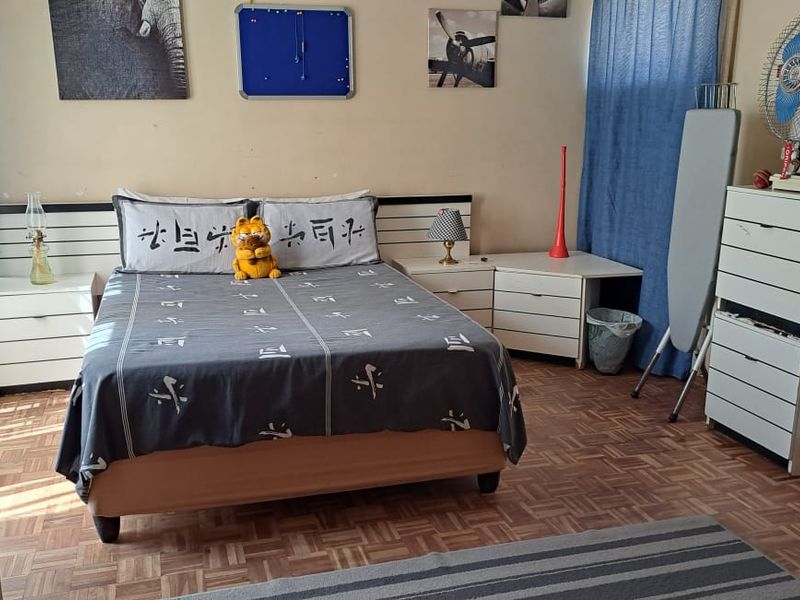 A bedroom featuring parquet flooring and a built-in headboard with integrated bedside storage.