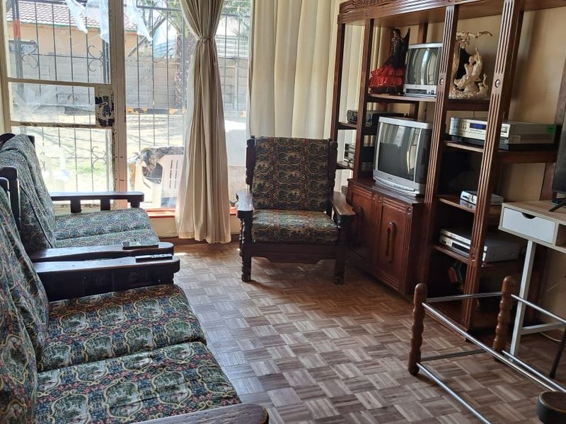 A living room featuring parquet flooring and a sliding glass door providing access to the exterior.