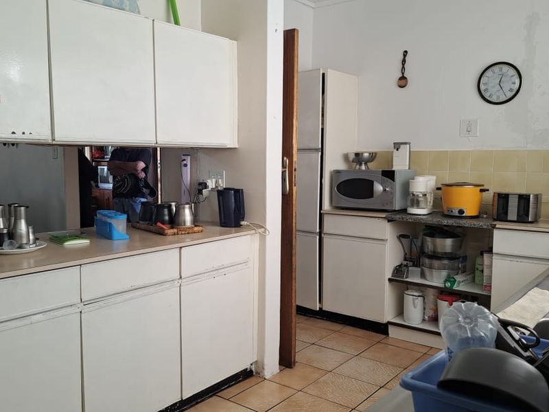 A functional kitchen featuring built-in cabinetry, tiled backsplash, and laminate countertops, currently showing signs of wear and requiring cosmetic updates.
