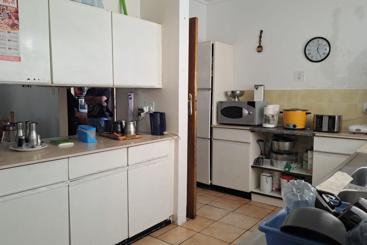 A functional kitchen featuring built-in cabinetry, tiled backsplash, and laminate countertops, currently showing signs of wear and requiring cosmetic updates.