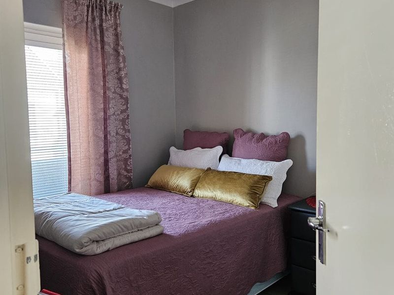 A compact bedroom featuring tiled flooring, neutral wall finishes, and window blinds, viewed from the doorway.