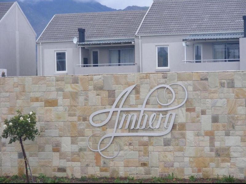 Front entrance view of the Amberg complex featuring a decorative stone wall and residential apartment buildings in the background.