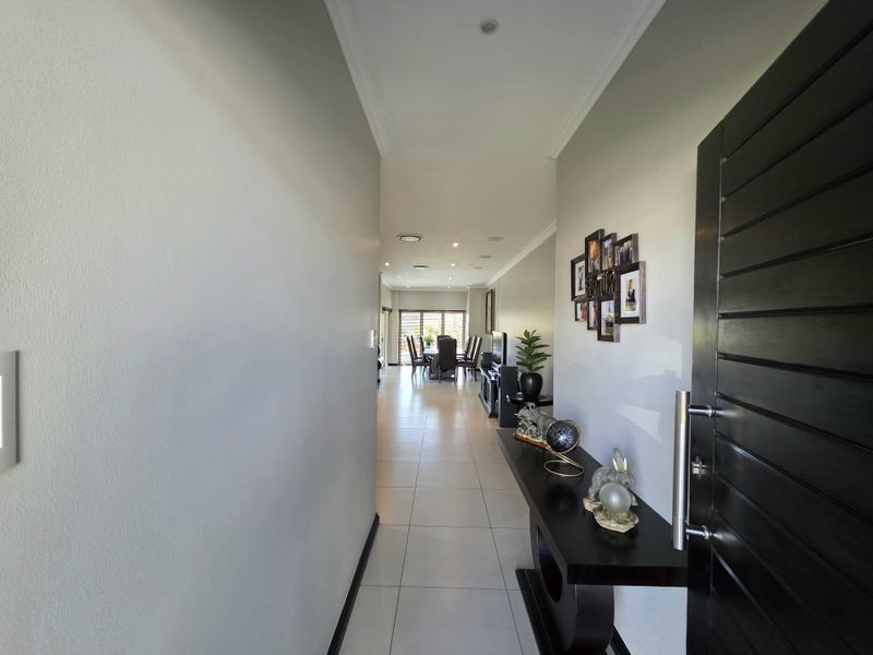 A welcoming entrance hallway featuring neutral walls, tiled flooring, and recessed lighting, leading directly into the open-plan living and dining area.