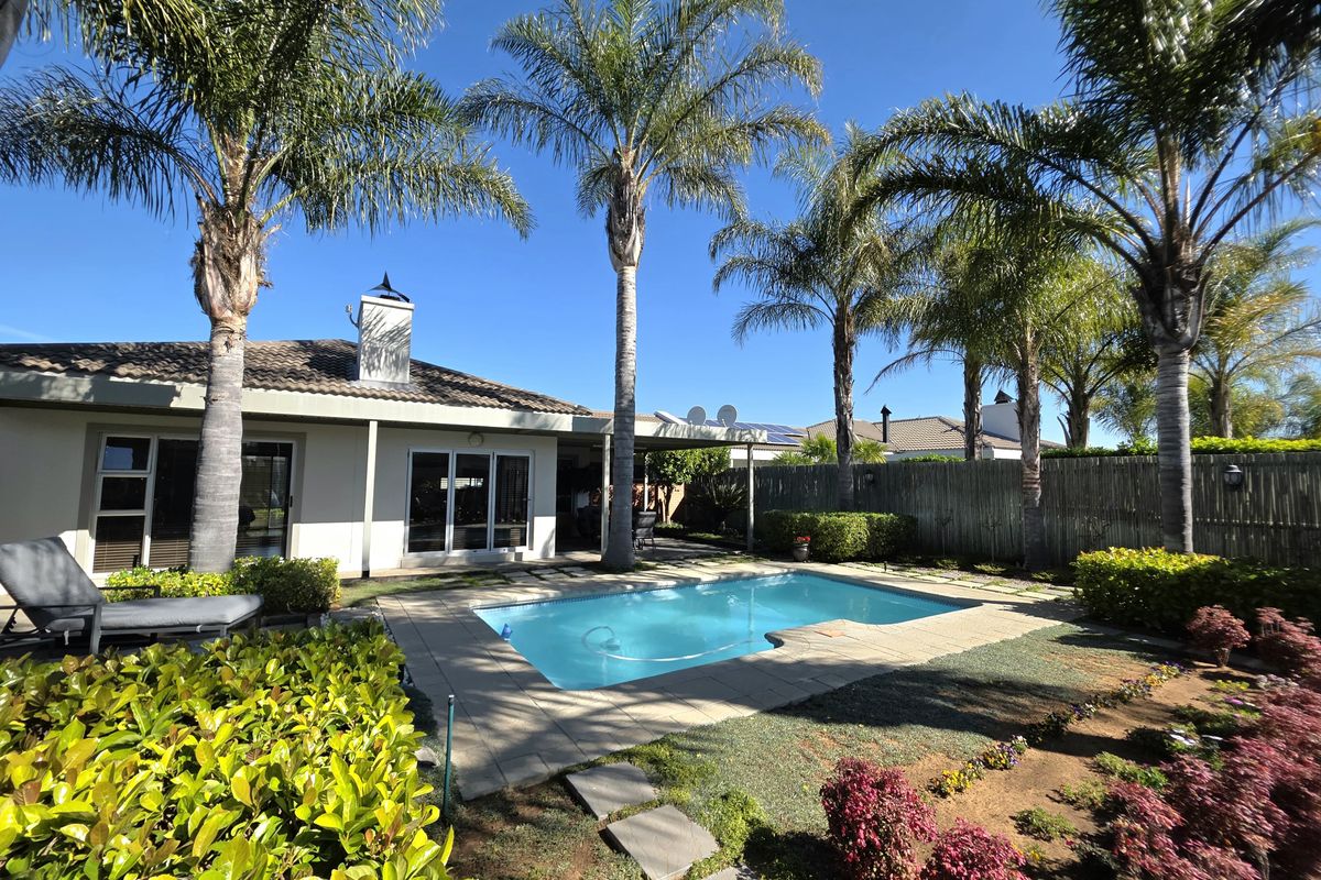 A well-maintained outdoor pool area featuring a paved surround, established palm trees, and direct access to the home via sliding glass doors.