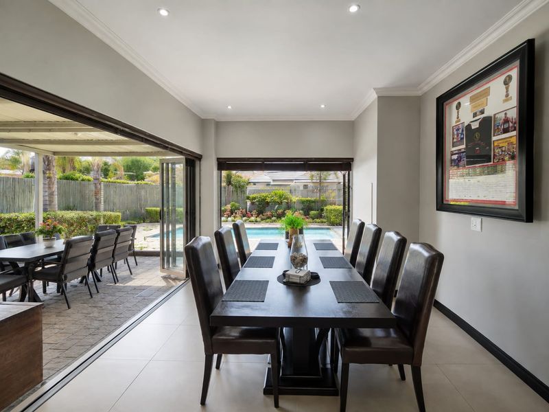 Spacious open-plan dining area featuring large bi-fold doors that seamlessly connect the interior to the outdoor patio and pool area.
