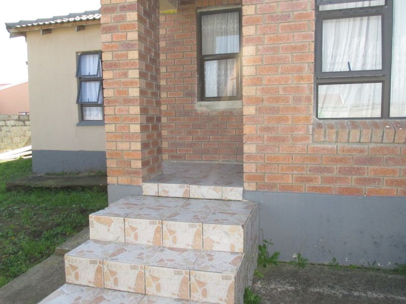 Front entrance of the house featuring face brick construction, tiled steps, and aluminium window frames.
