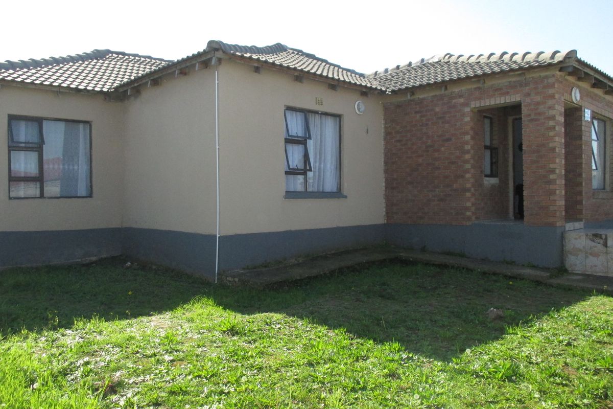 Rear view of a single-story residential house featuring a combination of plastered and brick exterior walls with tiled roofing and casement windows.