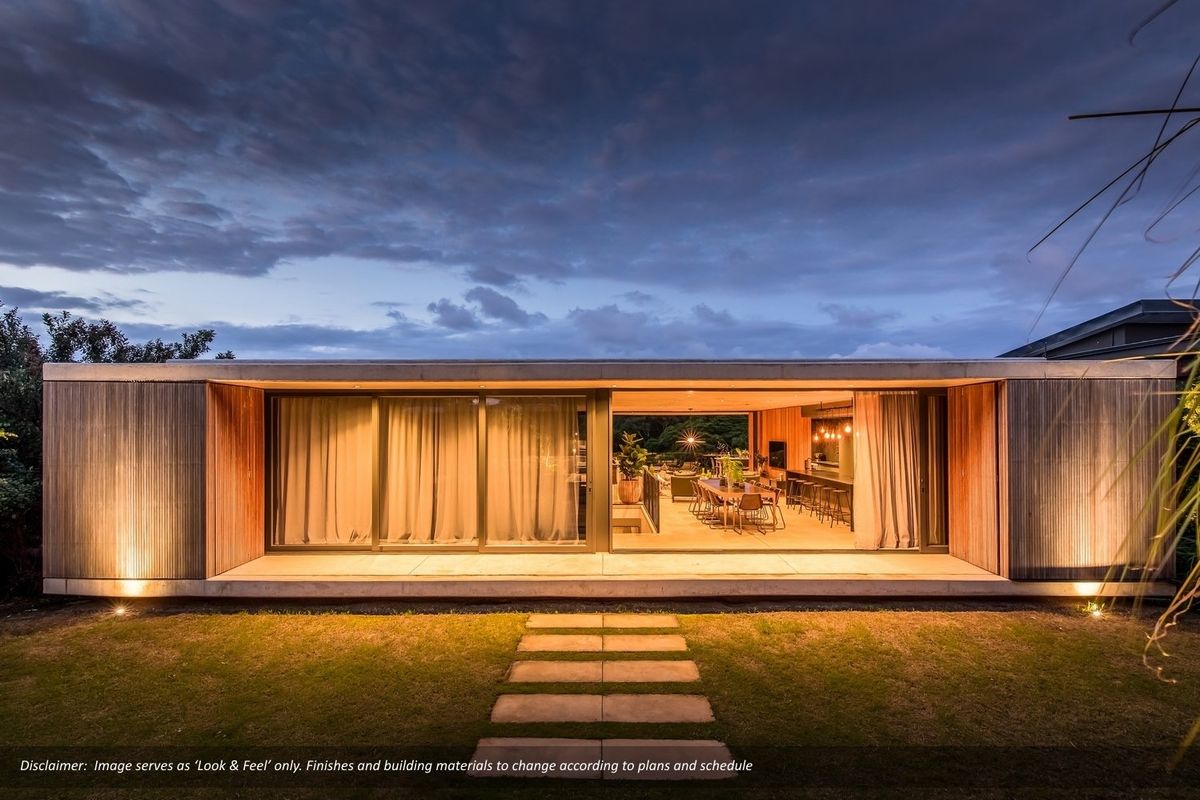 Modern rear elevation featuring expansive sliding glass doors, timber cladding, and a concrete patio overlooking a landscaped garden at dusk.