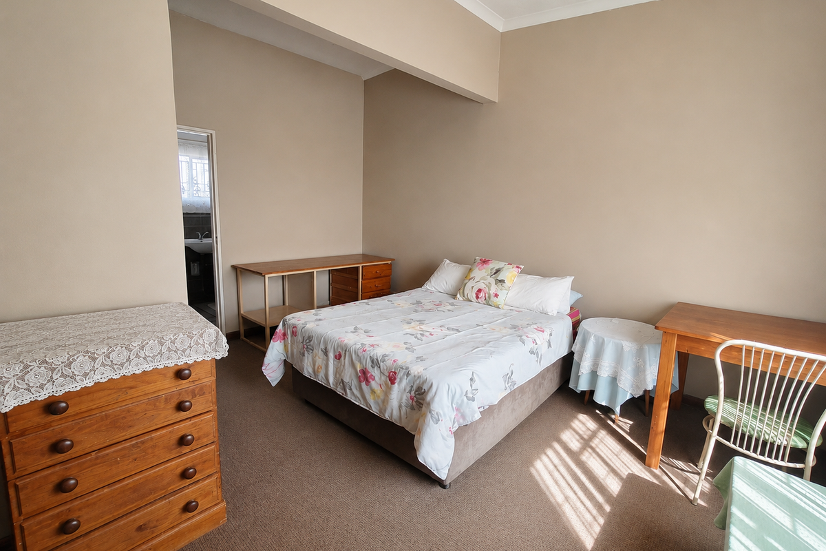 A spacious bedroom featuring neutral wall tones, carpeted flooring, and an adjoining en-suite bathroom access.