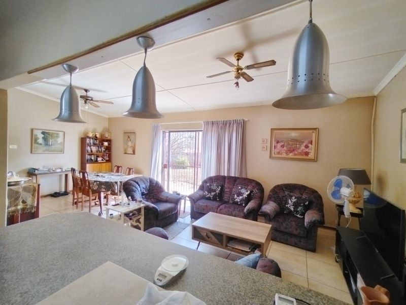 Open-plan living and dining area featuring tiled floors, ceiling fans, and direct access to the exterior through a sliding security door.