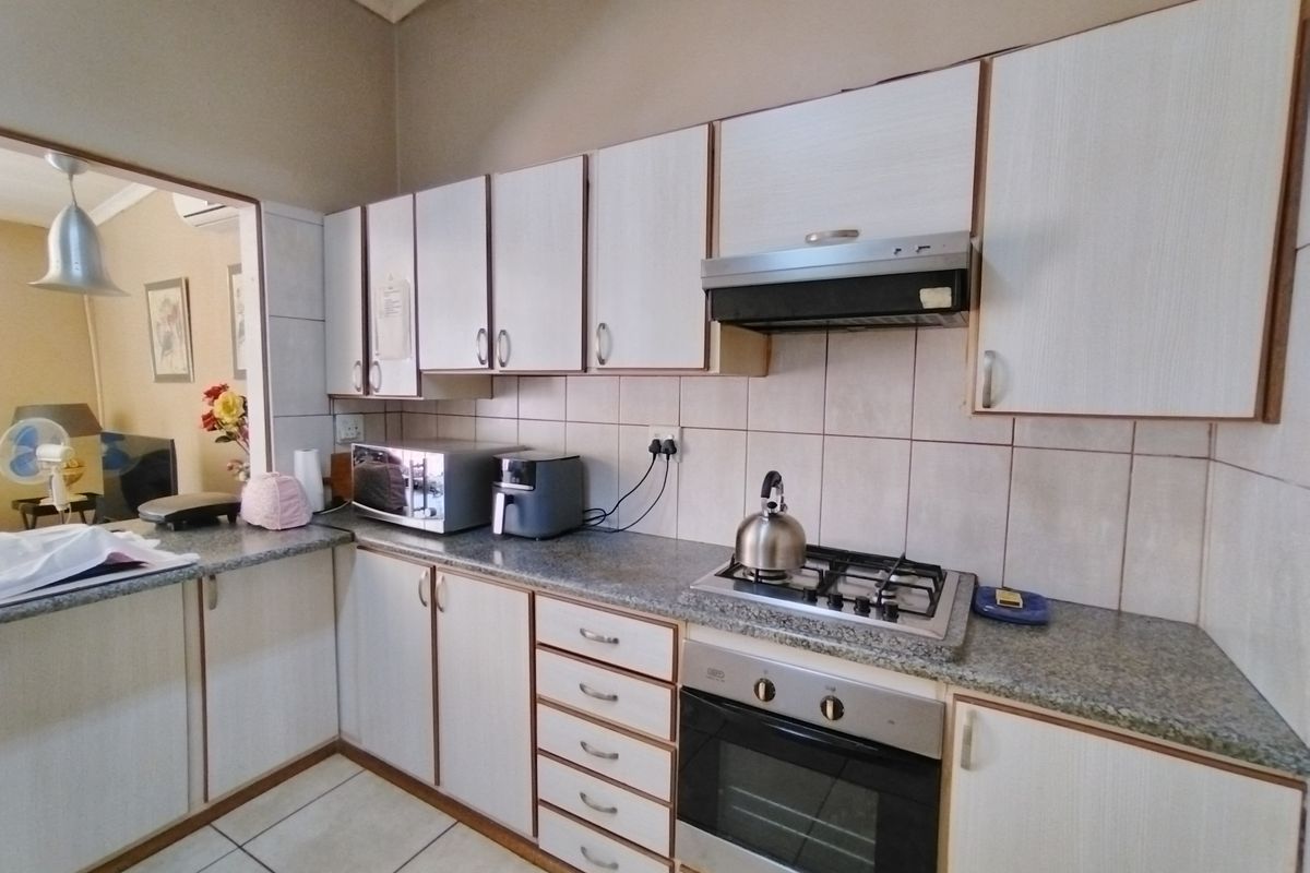 A functional kitchen featuring built-in cabinetry, granite countertops, a gas hob, and an integrated oven with an extractor fan.