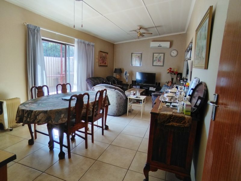 Open-plan living and dining area featuring tiled flooring, a ceiling fan, and a split-system air conditioner with access to the exterior via sliding doors.