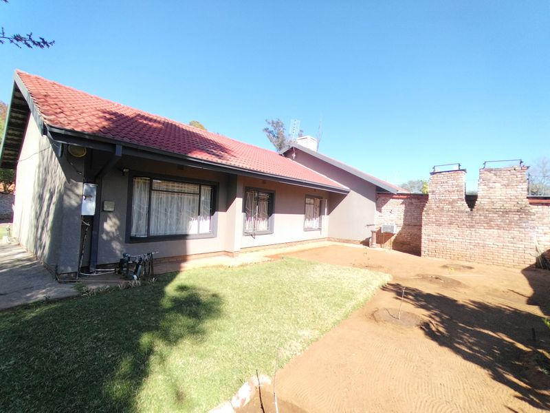 Rear view of the house featuring a tiled roof, brick chimney, and a garden area with lawn and exposed soil.
