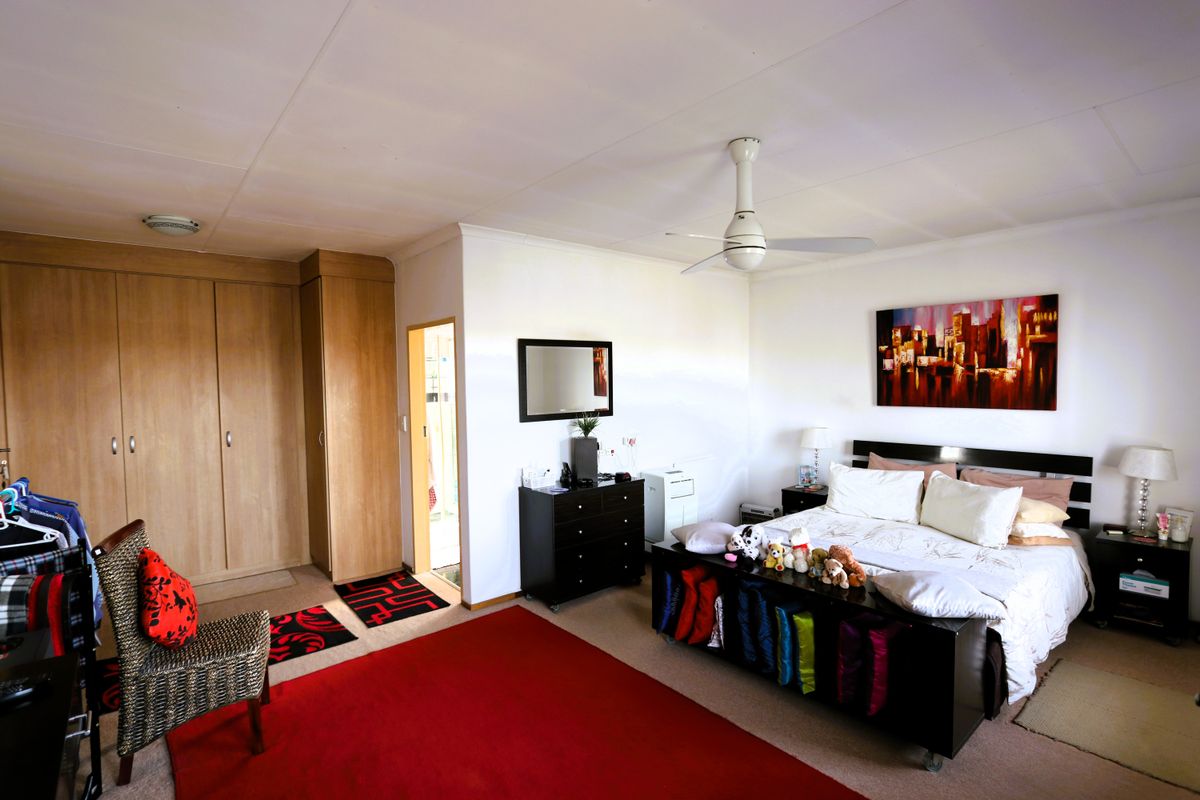 Spacious bedroom featuring built-in wooden cupboards and a ceiling fan, offering a functional layout with neutral wall finishes.