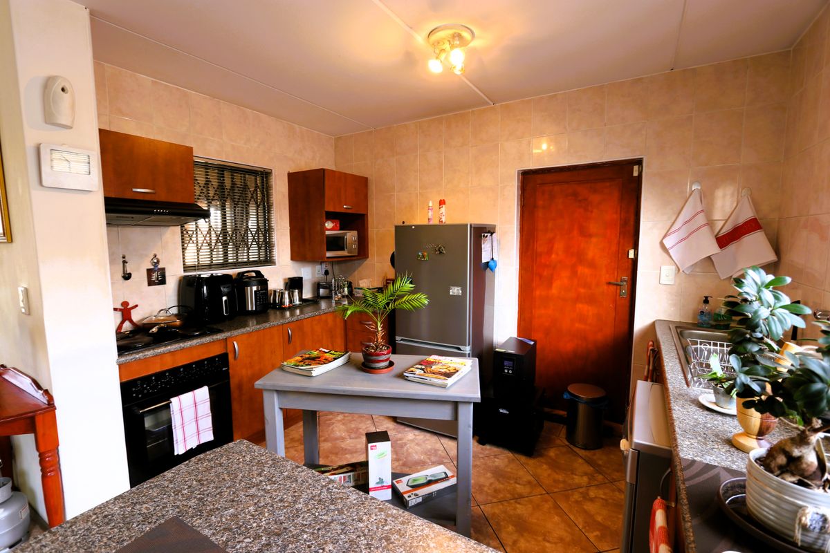 A functional kitchen featuring wood-finish cabinetry, granite countertops, tiled backsplash, and built-in oven with extractor fan.