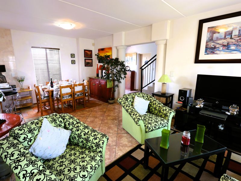 Open-plan living and dining area featuring tiled flooring, decorative columns, and a staircase leading to the upper level.