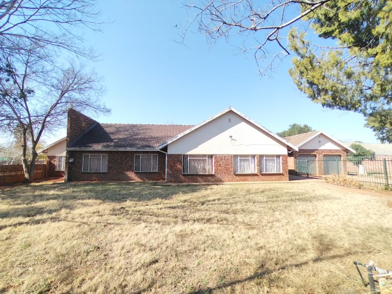 Front view of a single-story brick house featuring a tiled roof, security bars on windows, and an attached double garage.