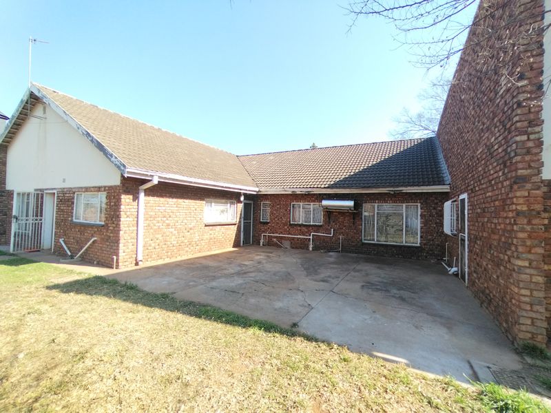 Rear view of the property featuring a face brick facade, concrete patio area, and a solar geyser installation.