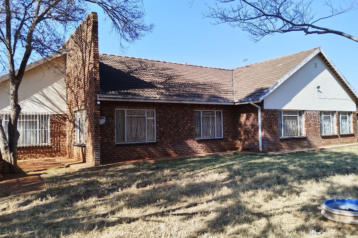 A view of the rear elevation of a face brick house featuring a tiled roof and security bars on the windows.