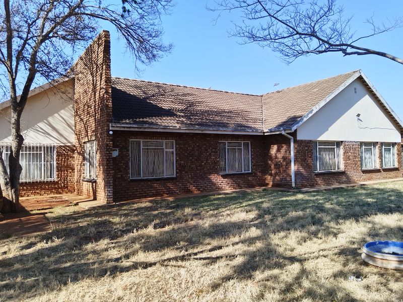A view of the rear elevation of a face brick house featuring a tiled roof and security bars on the windows.