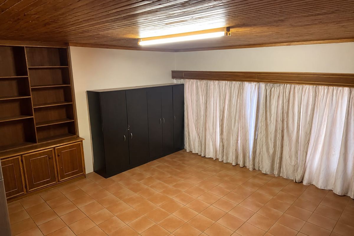 A bedroom featuring tiled flooring, a timber tongue and groove ceiling, and built-in wooden shelving units.