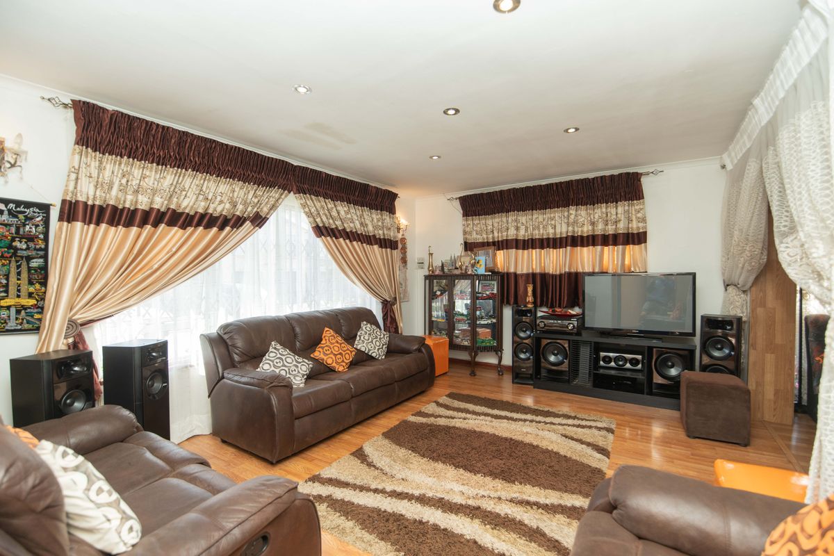A living room featuring laminate flooring and recessed downlighting, with a visible water stain on the ceiling.