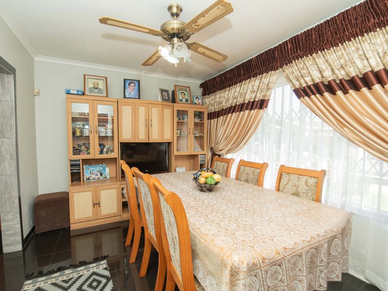 A dining room featuring tiled flooring, a ceiling fan, and built-in cabinetry, providing a functional space for family meals.