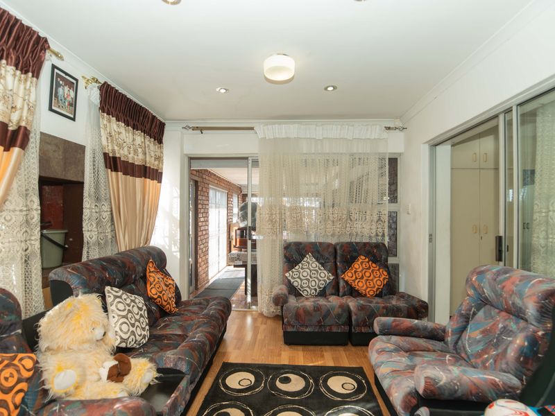 A living room featuring laminate flooring, recessed lighting, and sliding glass doors providing access to an adjacent patio area.
