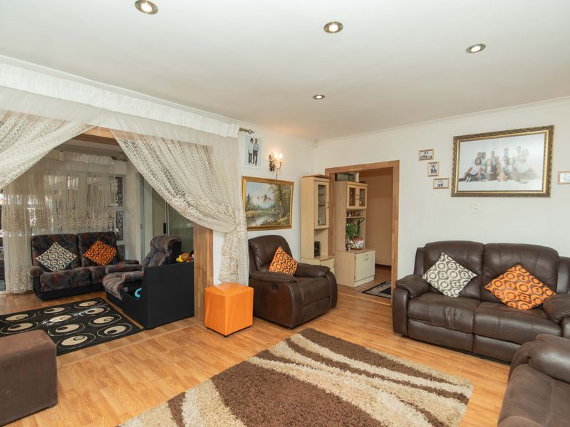 Spacious living room featuring laminate flooring, recessed downlighting, and coved cornicing, providing a comfortable and functional family living space.