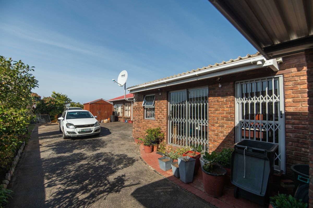 Rear exterior view of the property featuring a brick facade, paved driveway, and secure sliding door access.