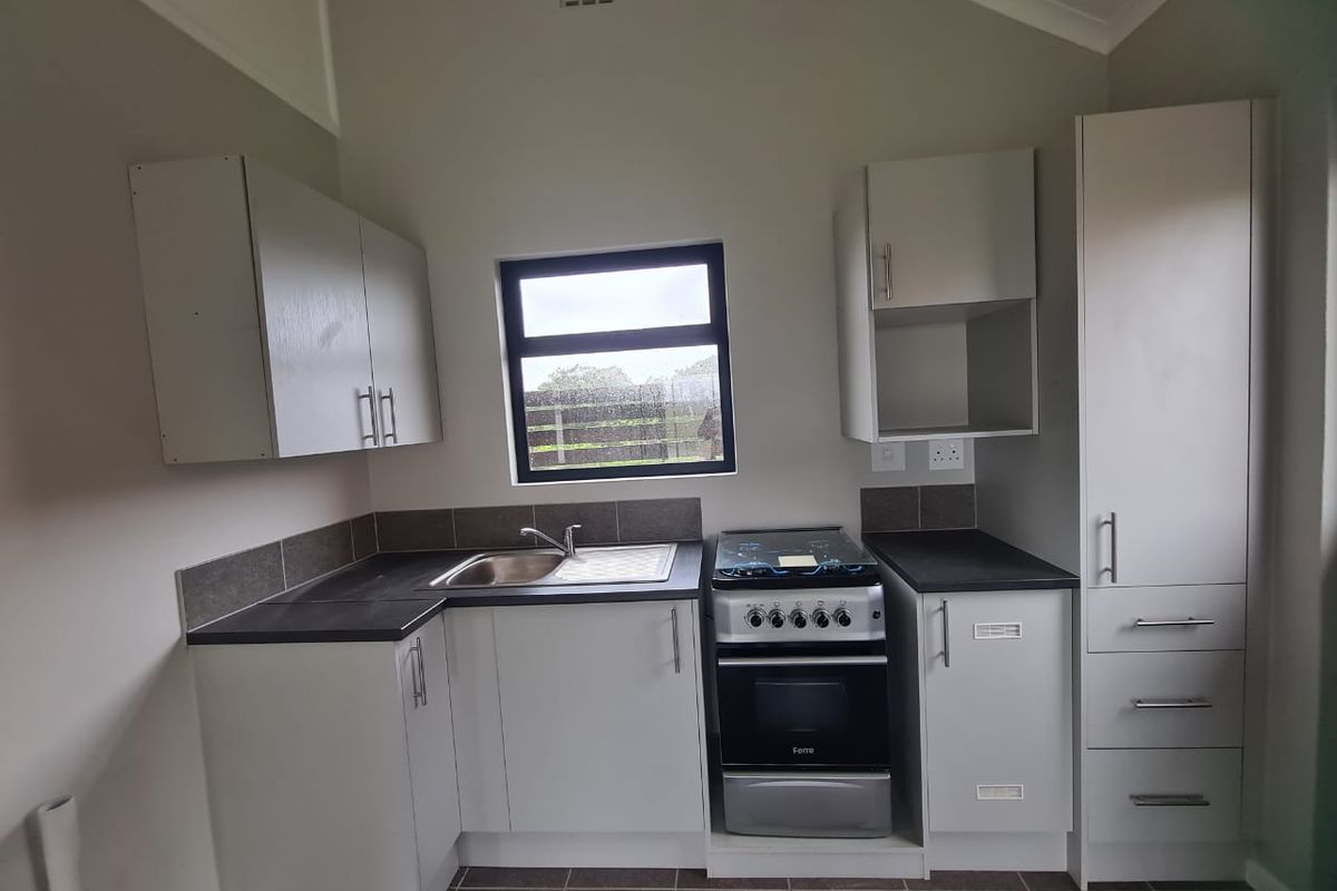 A clean and functional kitchen featuring modern cabinetry, a stainless steel sink, a freestanding stove, and tiled splashbacks with neutral finishes.