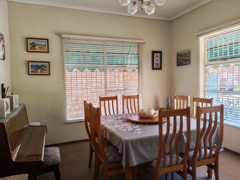 A dining room featuring carpeted flooring, coved ceilings, and large windows with venetian blinds, providing a functional space for family meals.