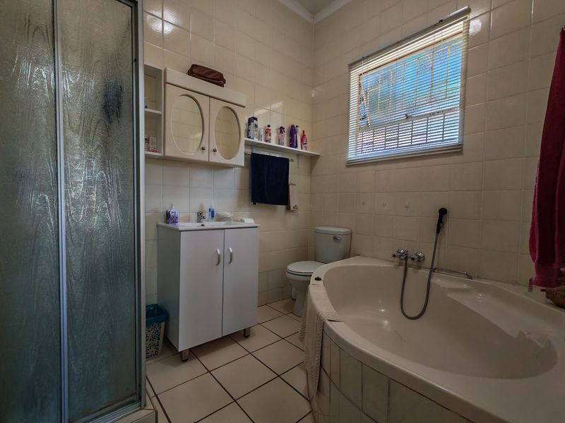 A dated bathroom featuring a corner bathtub, separate shower enclosure, vanity basin, and toilet with tiled finishes throughout.