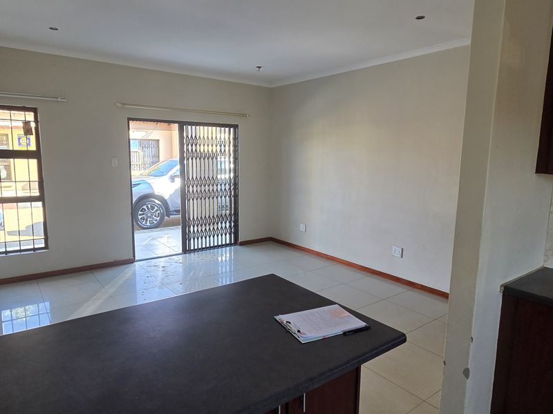 An open-plan living and kitchen area featuring tiled flooring, dark wood cabinetry, and a sliding door leading to the exterior.