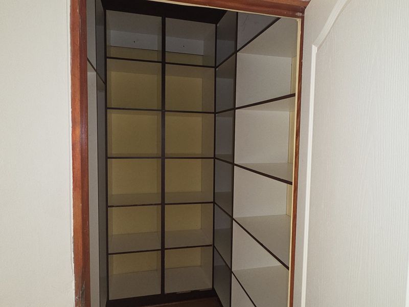 A walk-in storage closet or pantry featuring extensive built-in shelving units with a wooden door frame.