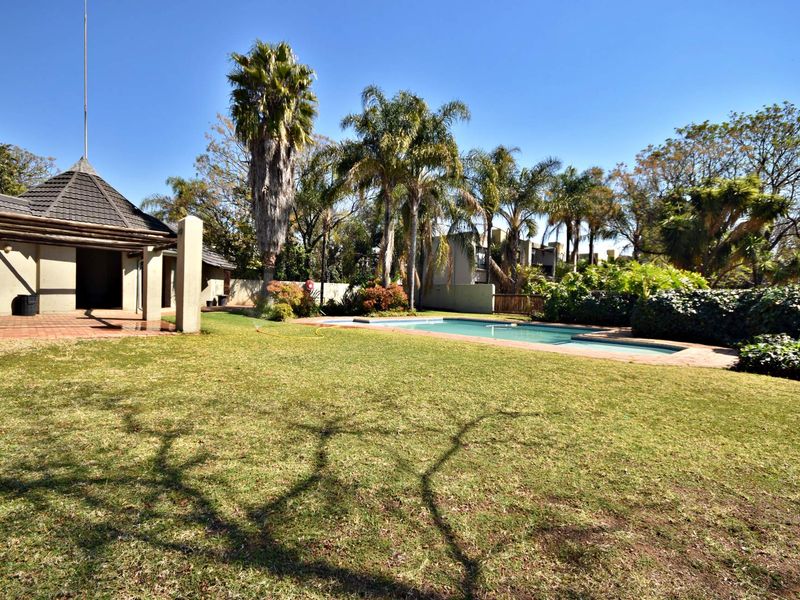 Spacious outdoor area featuring a swimming pool, paved patio space, and a well-established garden with mature trees and boundary walls.