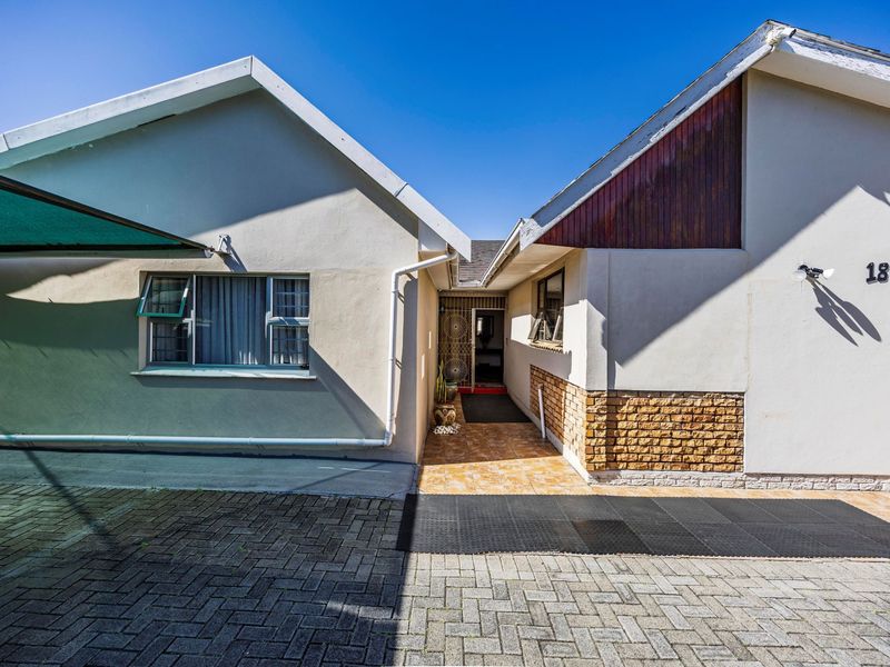 Front entrance view of the property featuring a paved driveway, tiled walkway, and secure gated entry point.