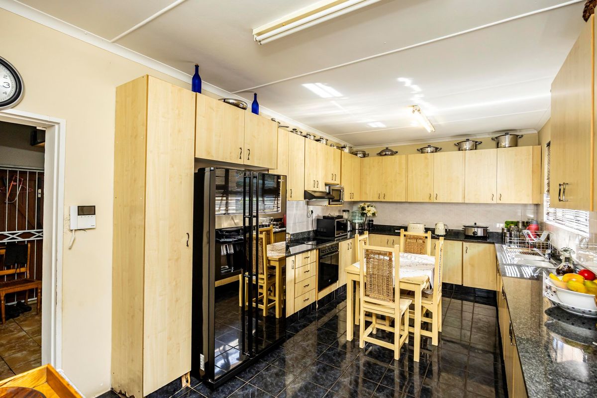 A functional kitchen featuring light wood cabinetry, dark granite countertops, tiled flooring, and integrated appliances, offering a practical layout for daily meal preparation.