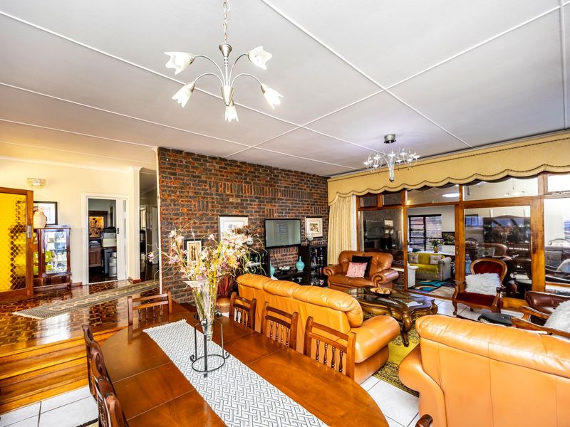 Spacious open-plan living and dining area featuring an exposed brick wall, parquet flooring, and large sliding glass doors leading to an enclosed patio.