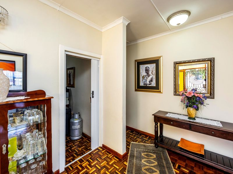 A well-maintained hallway featuring classic parquet flooring, neutral walls, and a sliding door leading to a utility area.