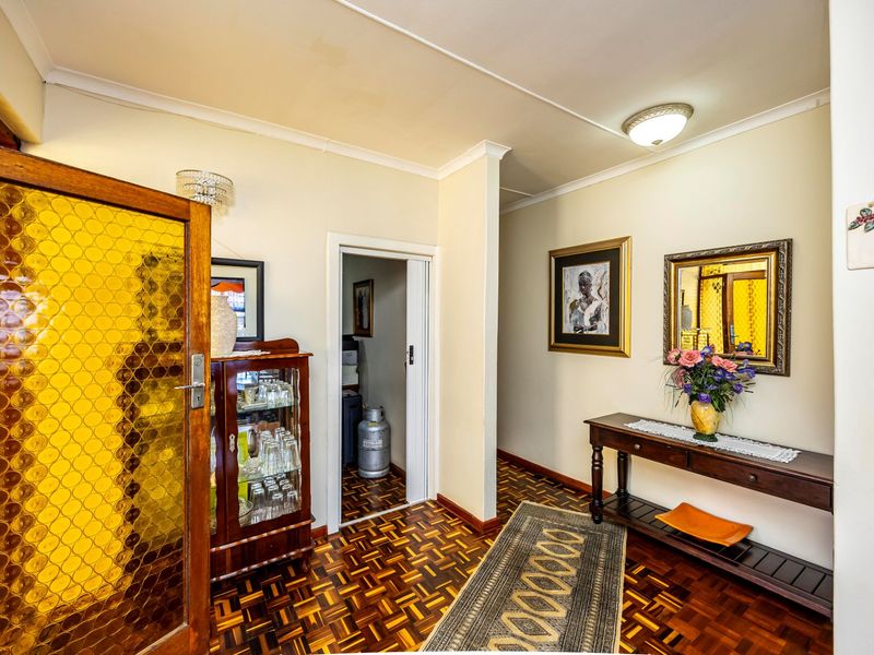 A welcoming entrance hall featuring classic parquet flooring, an exposed brick accent wall, and a textured glass door leading into the home.