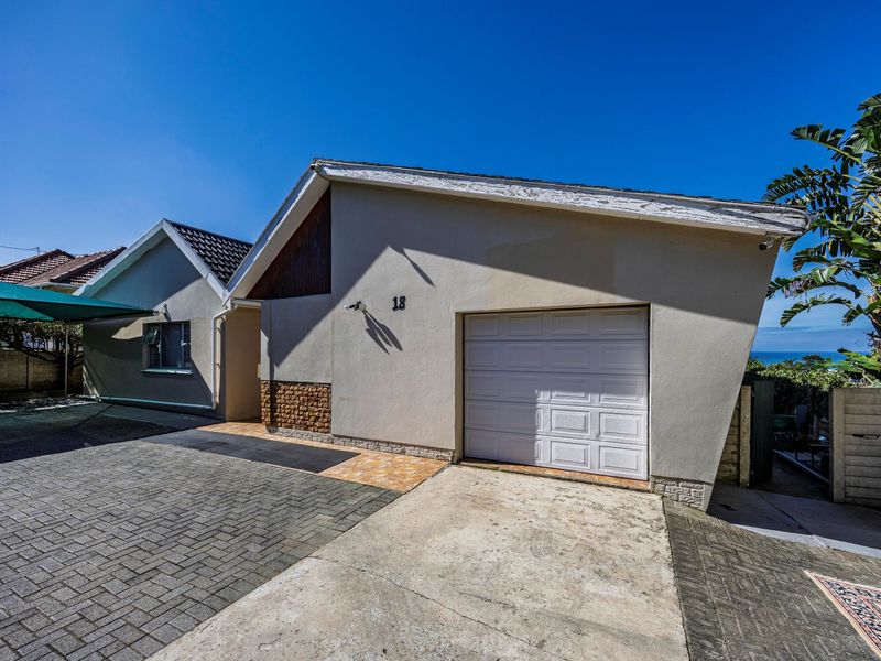 Front exterior view of the house featuring a single garage, paved driveway, and a covered carport area.