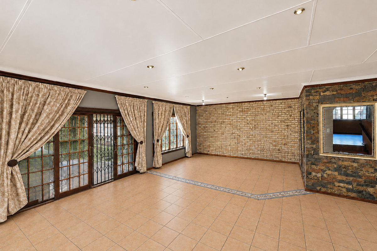 Spacious living area featuring tiled floors, an exposed brick wall, stone cladding accents, and large sliding doors providing access to the exterior.