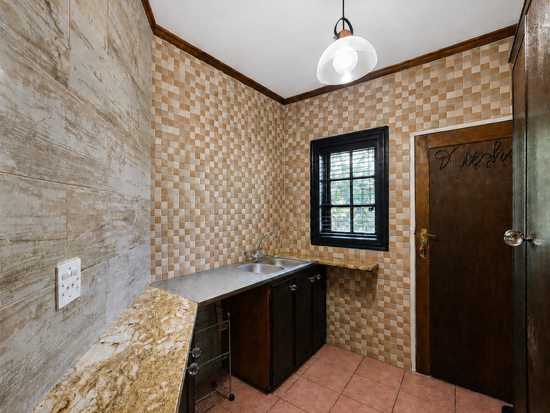 A functional scullery area featuring a stainless steel sink, built-in cabinetry, and tiled finishes, providing a dedicated space for food preparation and wash-up.