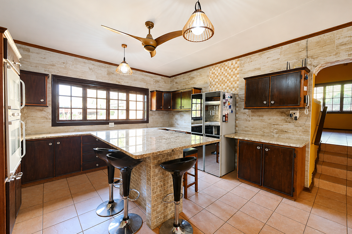 Spacious kitchen featuring granite countertops, dark wood cabinetry, tiled backsplash, and a central island with breakfast bar seating.
