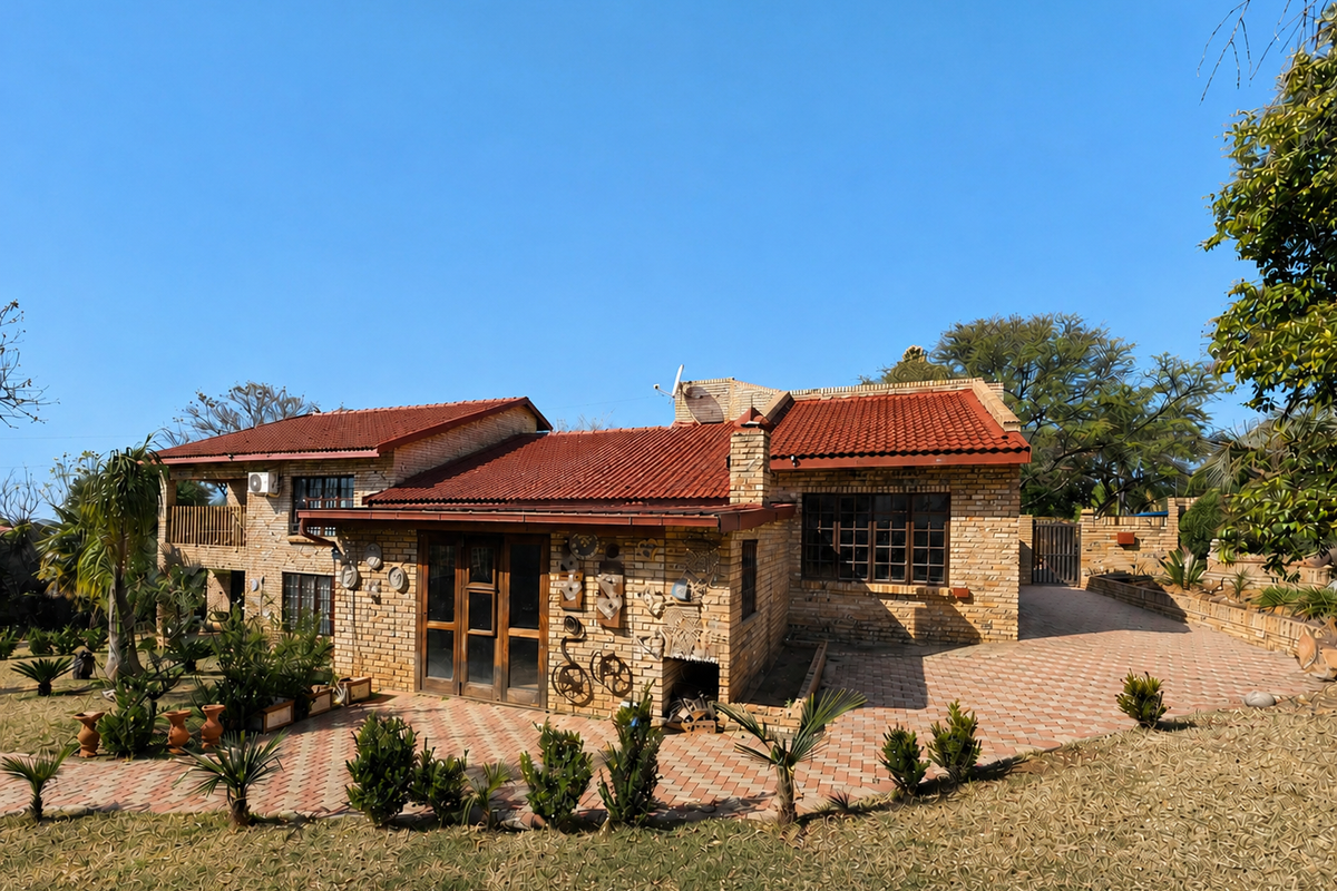 Rear view of a brick house featuring a terracotta tiled roof, paved patio area, and established garden surroundings.