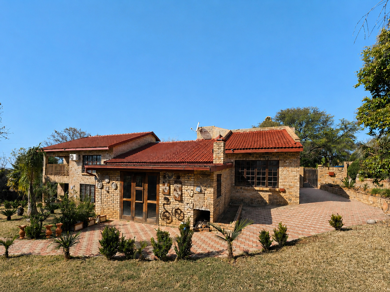Rear view of a brick house featuring a terracotta tiled roof, paved patio area, and established garden surroundings.