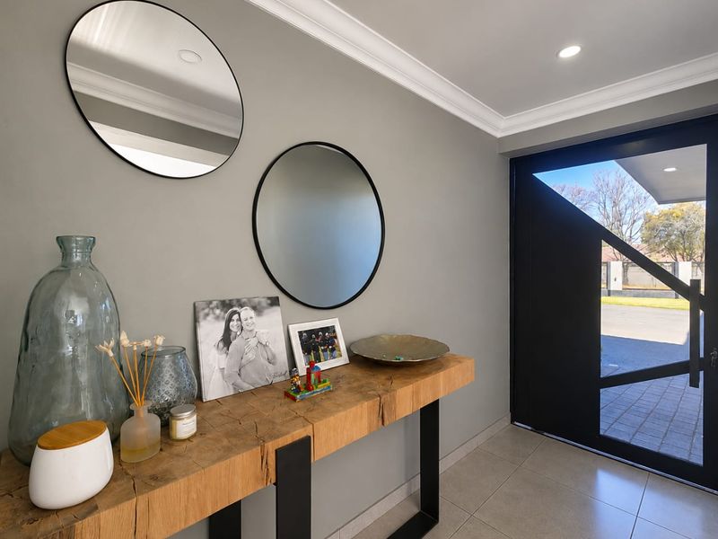 A bright and modern entrance hall featuring tiled flooring, recessed downlighting, crown molding, and a contemporary front door.